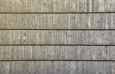 Gray wooden roof tiles background texture. A close up of old gray roof covered with wooden tiles.