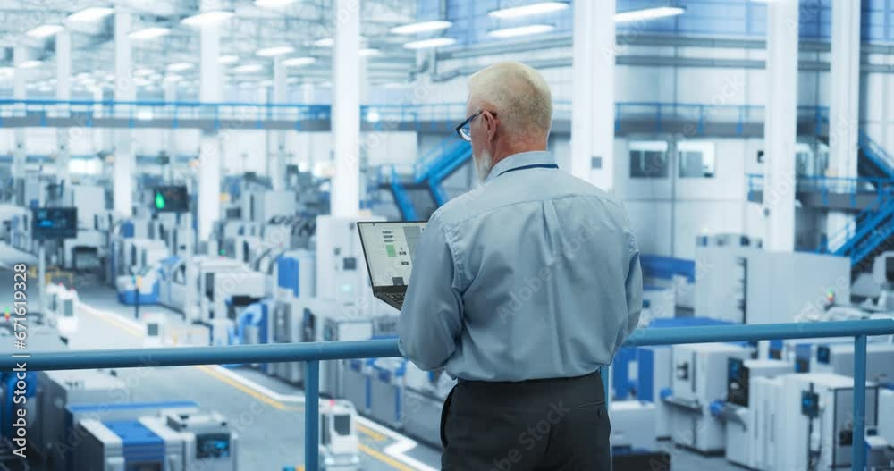 Poster Middle Aged Engineer Monitoring and Analyzing Conditions at an Automated Modern Electronics Factory with Mobility Robots Working with the Help of Artificial Intelligence Software. Back View Footage