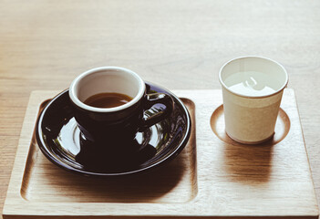 Hot coffee menu:1 shot espresso served with cold water on wooden table,An energizing and refreshing drink.copy space on top (cup of hot aromatic espresso placed)