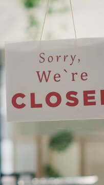 Vertical video Sorry we are closed sign in empty clothing store in mall with fast fashion clothes following the latest trends. Message on fashion boutique door announcing customers that shop is closed