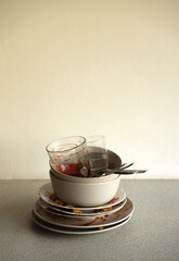 Stack of dirty dishes with food leftovers on the table after meal. Banquet ending concept. Unwashed dishes.