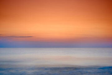 Fototapeta premium Copyspace seascape of an orange sunset on the west coast of Jutland in Loekken, Denmark. Sun setting on the horizon on an empty beach at dusk over the ocean and sea at night. Sunrise in the morning