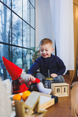 A 2-year-old boy sits on the windowsill in the new year. New Year's atmosphere at home. The child is waiting for the new year.