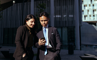 Couple of colleagues looking at phone screen together during lunch break, wireless connection concept