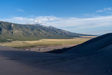 Fototapeta na wymiar View from the top at golden hour and sunset at Great Sand Dunes National Park in Colorado on a sunny summer evening, with mountains in the background
