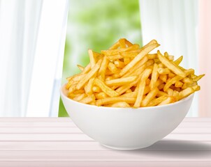 Plate of tasty hot French fries on the desk