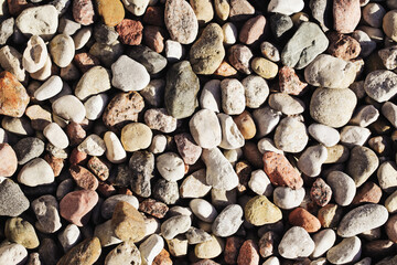 Different colors stones background. Small rocks texture. Sunlight rocks. Walking path made with pebble stones. Gravel backdrop.