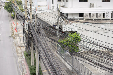 On the side of a road in Thailand there is an electric pole with a mess of wires and buildings and...