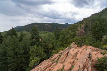 View of mountains, trees, and red rocks from Section 16 and Palmer Loop Hiking Trail in Colorado Spring, CO on a cloudy and overcast summer day