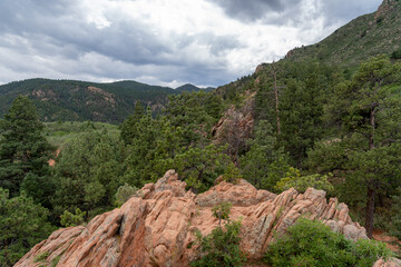 Fototapeta na wymiar View of mountains, trees, and red rocks from Section 16 and Palmer Loop Hiking Trail in Colorado Spring, CO on a cloudy and overcast summer day