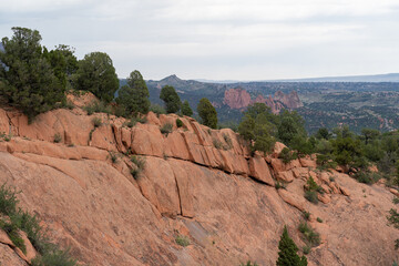 View of mountains, trees, and red rocks from Section 16 and Palmer Loop Hiking Trail in Colorado Springs, CO on a cloudy and overcast summer day - with Garden of the Gods in the background