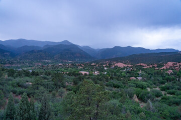 A view of a rainstorm over Pike's Peak and other blue misty mountains on a cloudy summer evening, as viewed from Garden of the Gods in Colorado Springs, CO
