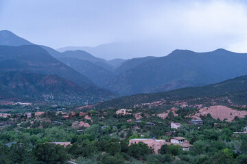 Fototapeta premium A view of a rainstorm over Pike's Peak and other blue misty mountains on a cloudy summer evening, as viewed from Garden of the Gods in Colorado Springs, CO