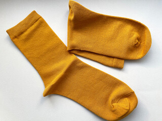Two orange new socks lie side by side, one is flat, the other is folded in half on a gray background, close-up, top view. Warm cotton socks. Style.