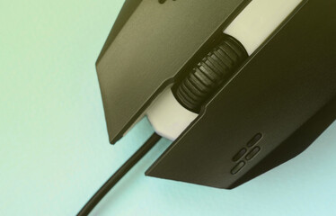 Closeup of a black gaming optical mouse on a blue background.