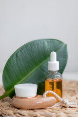 Essential oil in a glass bottle with green leaves on a white background