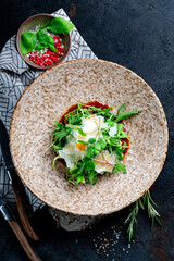 Salad with herbs and prunes on a ceramic plate on a dark background. Fresh healthy salad with parmesan and arugula, top view