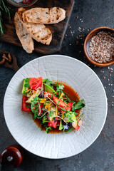 Italian salad with fresh vegetables. Mixed salad of tomatoes, cucumbers, avocado and greens, top view