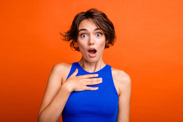 Photo of funky shocked lady wear blue singlet open mouth arm chest isolated orange color background