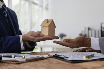 A real estate agent discusses the terms of a home purchase contract and asks the client to sign the documents to legally enter into a contract. Selling a home. Close-up photo.