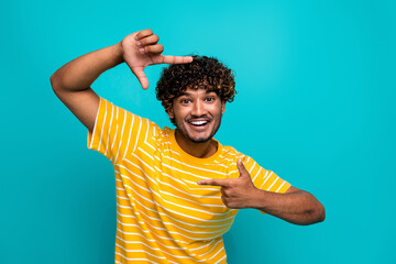 Photo portrait of nice young male fingers frame photo gesture dressed stylish striped yellow garment isolated on cyan color background