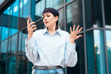 Portrait of a young woman talking in anger on her mobile to her boyfriend about ending their...