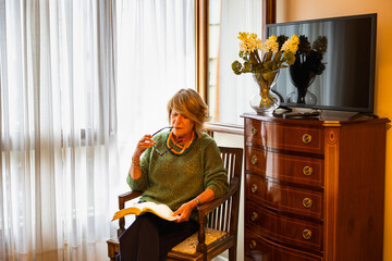 Older woman sitting in her bedroom reading a book