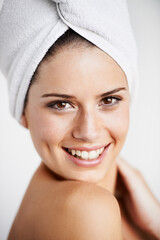 Happy, skincare and woman with towel in a studio for health, wellness and natural face routine. Smile, beauty and portrait of young female model with facial dermatology treatment by gray background.