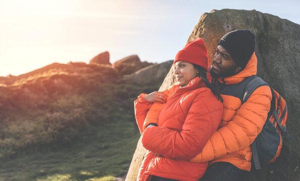 Portrait of happy couple in love posing on a rocks whili hiking on the mountain trail at cold autumn evening.  Love, hiking and active lifestyle concept toned image
