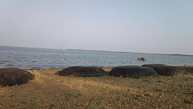 A wide shot shows fishing boats or coracles boats kept at lake banks at sunset