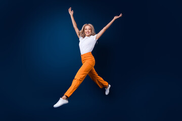 Fototapeta na wymiar Full length photo of adorable cute girl gymnast wear trendy outfit jump up raise hands empty space isolated on dark blue color background