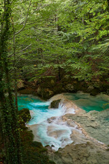 The waterfalls and crystal clear, blue, turquoise and green waters of the Nacedero del Urederra, with its beech forest with its autumn colors in the Sierra de Urbasa-Andía. Navarre. Spain