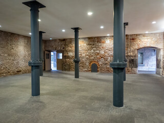 Industrial heritage interior; a renovated building with iron support columns, stone floors and...