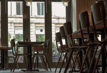 Beautiful design inside of Restaurant. Decorated with wooden table with chairs next to glass doors. Space for text, Selective focus.