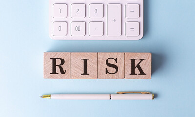 RISK on wooden cubes with pen and calculator, financial concept