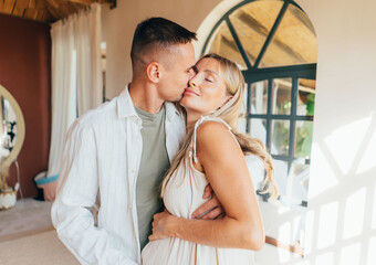 Young pregnant woman with her husband are hugging and kissing.