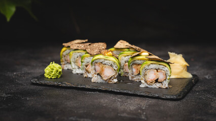 Stylish serving of avocado rolls on a black stone plate.