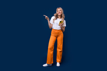 Full length photo of lovely glad stylish girl presenting empty space modern technology store isolated on dark blue color background