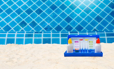 Water tester on sandy beach over clear swimming pool water, water quality testing, pool maintenance, water test kit