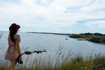 Elegant lady standing alone on the cliff edge, watching the horizon in calm contemplation, embracing freedom, discovery, and peaceful beginnings by the coastal seascape.