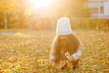 Happy girl playing with autumn leaves. Happy child walking and having fun in fall backyard.