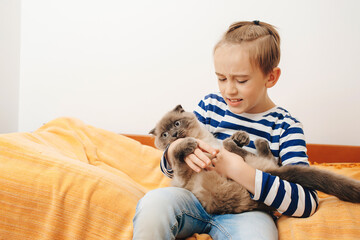 Happy kid hugging his cat. Boy relaxing on the bed with pet. Childhood, true friendship and home pet.