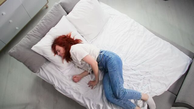 carefree young woman spends time at home lying on bed in room, changing speed in frame, time lapse and slow motion