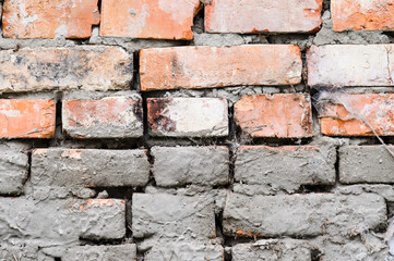 The background of the wall is made of brown bricks, laid out from a cement-sand mortar