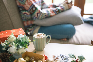 Happy young woman using smartphone mobile addict spending time in front of Christmas tree at home celebrating new year and Christmas