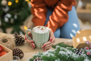 Woman holding cup of aromatic cocoa with marshmallows. Christmas eve with cup of tasty hot chocolate cozy holiday atmosphere at home