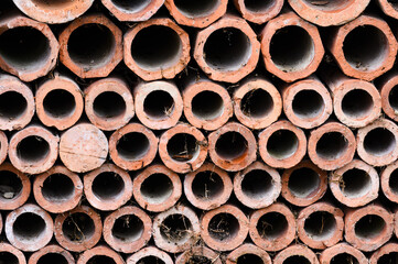 Drainage old clay pipes for sewage stacked in a texture with holes