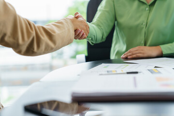 Business People shaking hands with unrecognizable colleague during successful making a deal meeting in the boardroom.