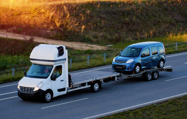 A side view of the tow truck with a damaged commercial vehicle after being in a traffic accident. Emergency roadside assistance.