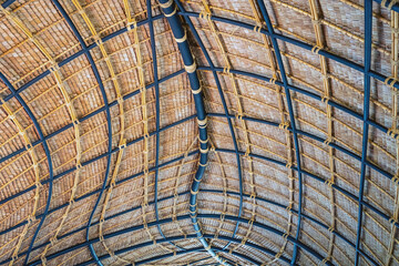 Beautiful thatched roof surface detail of mixed materials pattern structure by weave pile straw with steel bars. .Roof​ made​ of​ straw. Pattern of under bamboo roof frame..Wooden thatched ceiling.